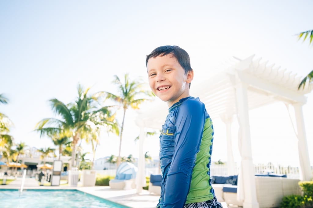 a young boy smiling as he heads towards the pool