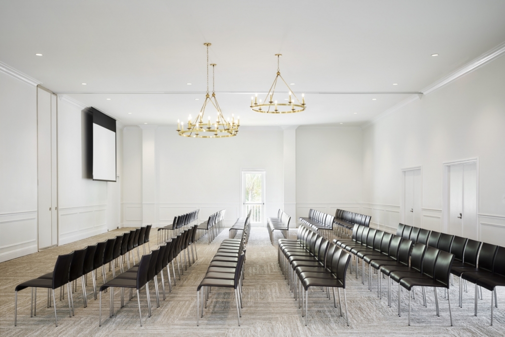 Bright ballroom set with rows of chairs and gold chandeliers