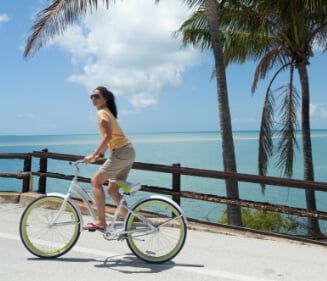 A Woman Biking Beside Some Palm Trees and the Ocean in the Florida Keys