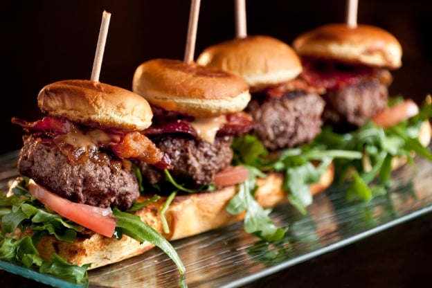 Four gourmet burger sliders on tray from Isla Bella Beach Resort