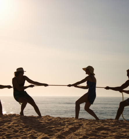 Guests playing tug-of-war on the beach at sunset
